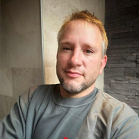 Photo de Jean-François(cadré sur son buste), artisan carreleur, posant fièrement devant l'une de ses réalisations.